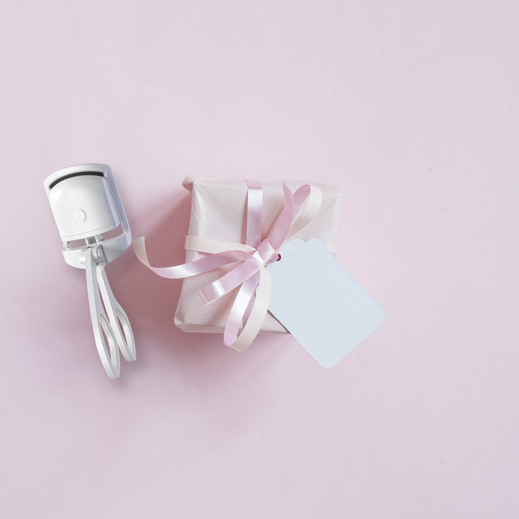 GlowCurl heated eyelash curler beside a ribbon-wrapped gift